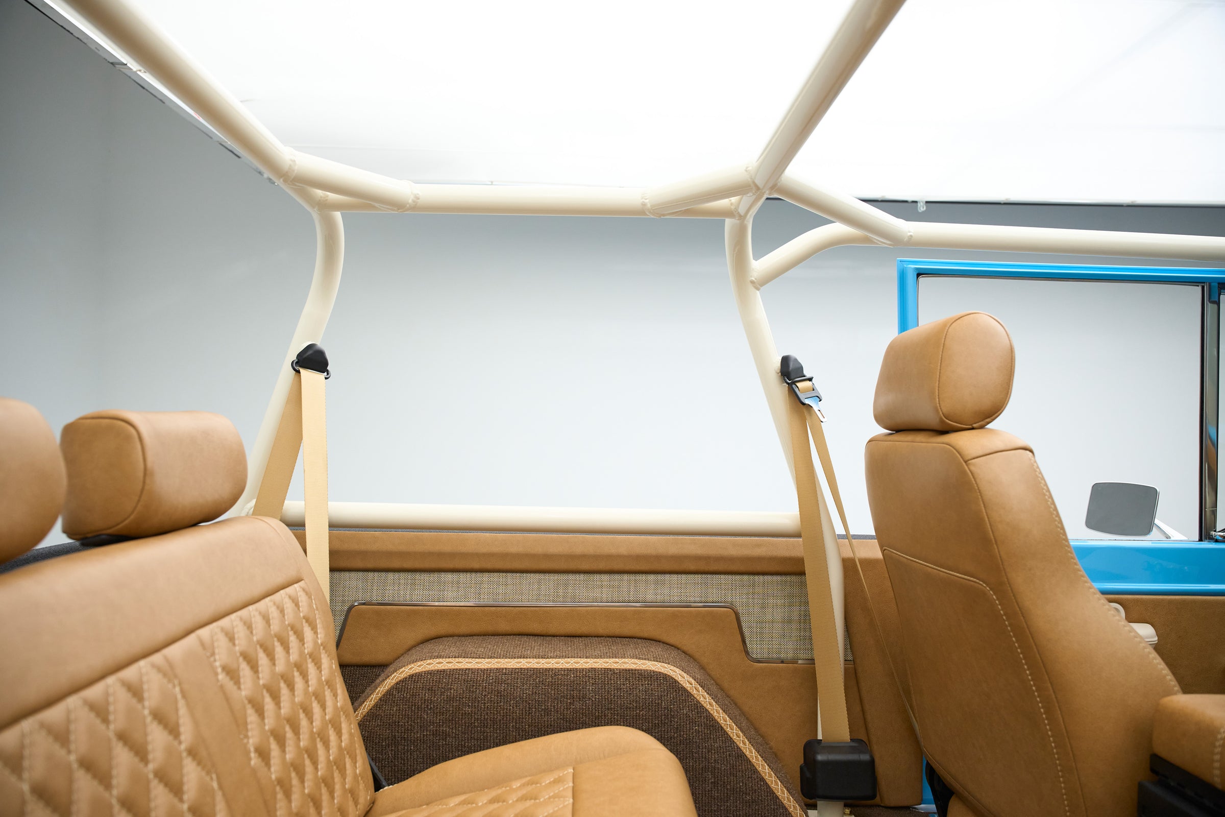 Classic Ford Bronco interior showing tan quilted seats and beige roll cage