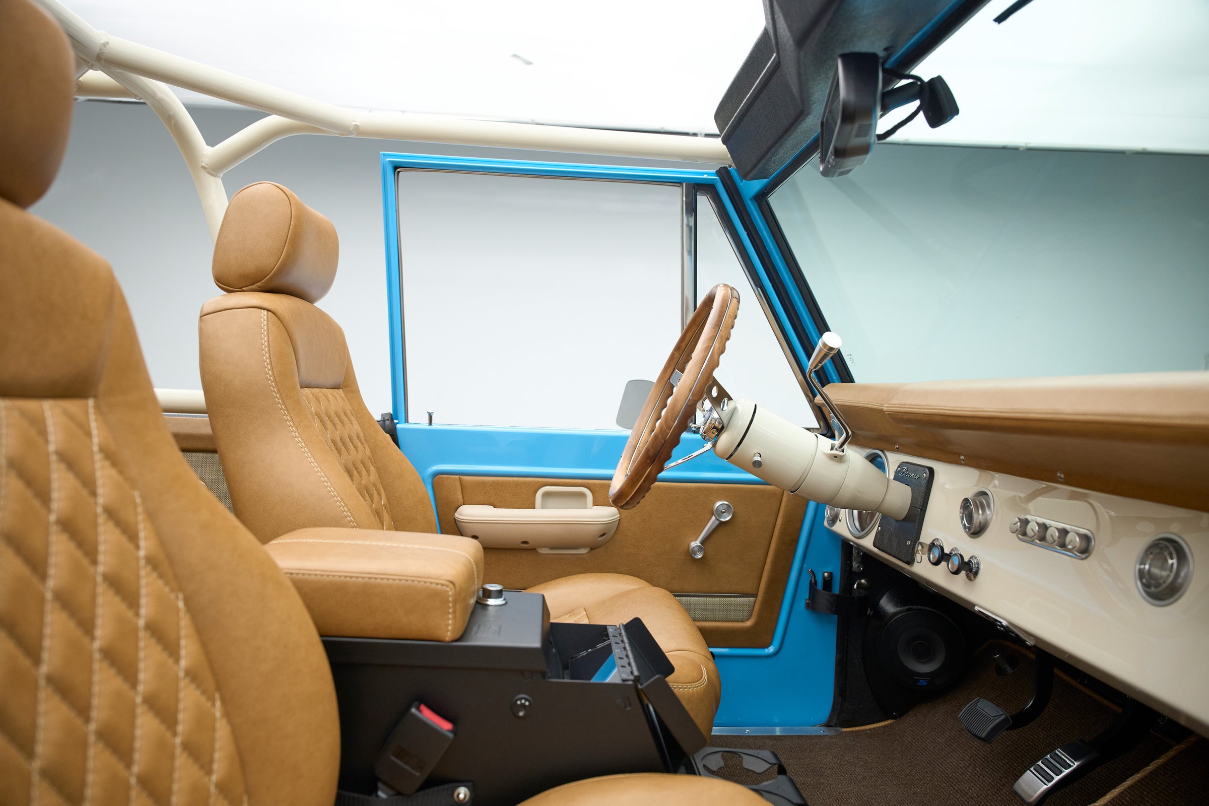 Tan leather front seats and steering wheel inside blue Classic Ford Bronco