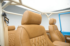 Close-up of tan leather front seats with beige roll cage in Classic Ford Bronco