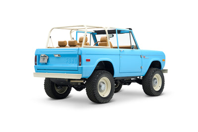 Side rear angle view of light blue Classic Ford Bronco with beige roll cage and seats