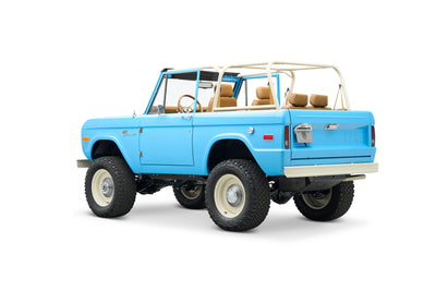 Side rear angle view of light blue Classic Ford Bronco with beige roll cage and seats