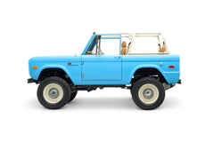 Side view of light blue Classic Ford Bronco with beige roll cage and seats