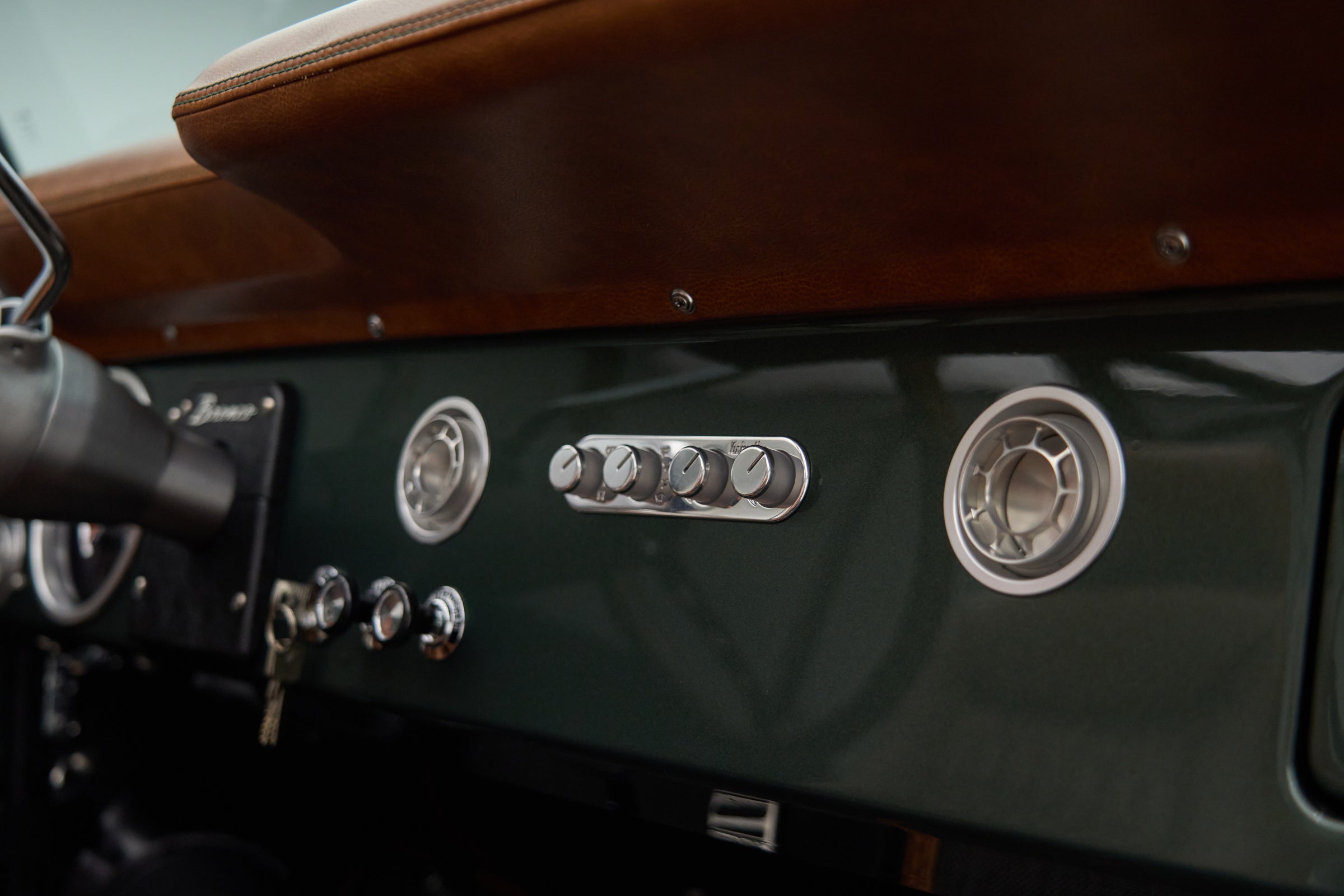 Close-up of dashboard vents and control knobs in dark green Classic Ford Bronco interior