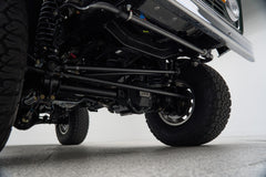 Underbody view of axle and suspension components with large off-road tires on Classic Ford Bronco