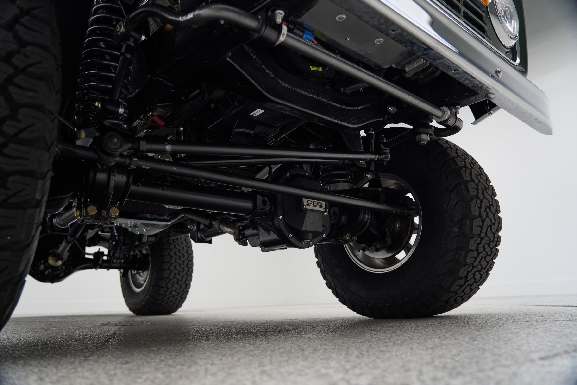 Underbody view of axle and suspension components with large off-road tires on Classic Ford Bronco