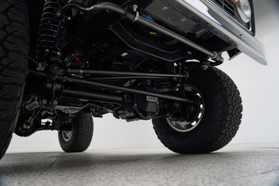Underbody view of axle and suspension components with large off-road tires on Classic Ford Bronco