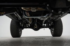 Underside view of front axle and suspension showing solid differential housing and tires