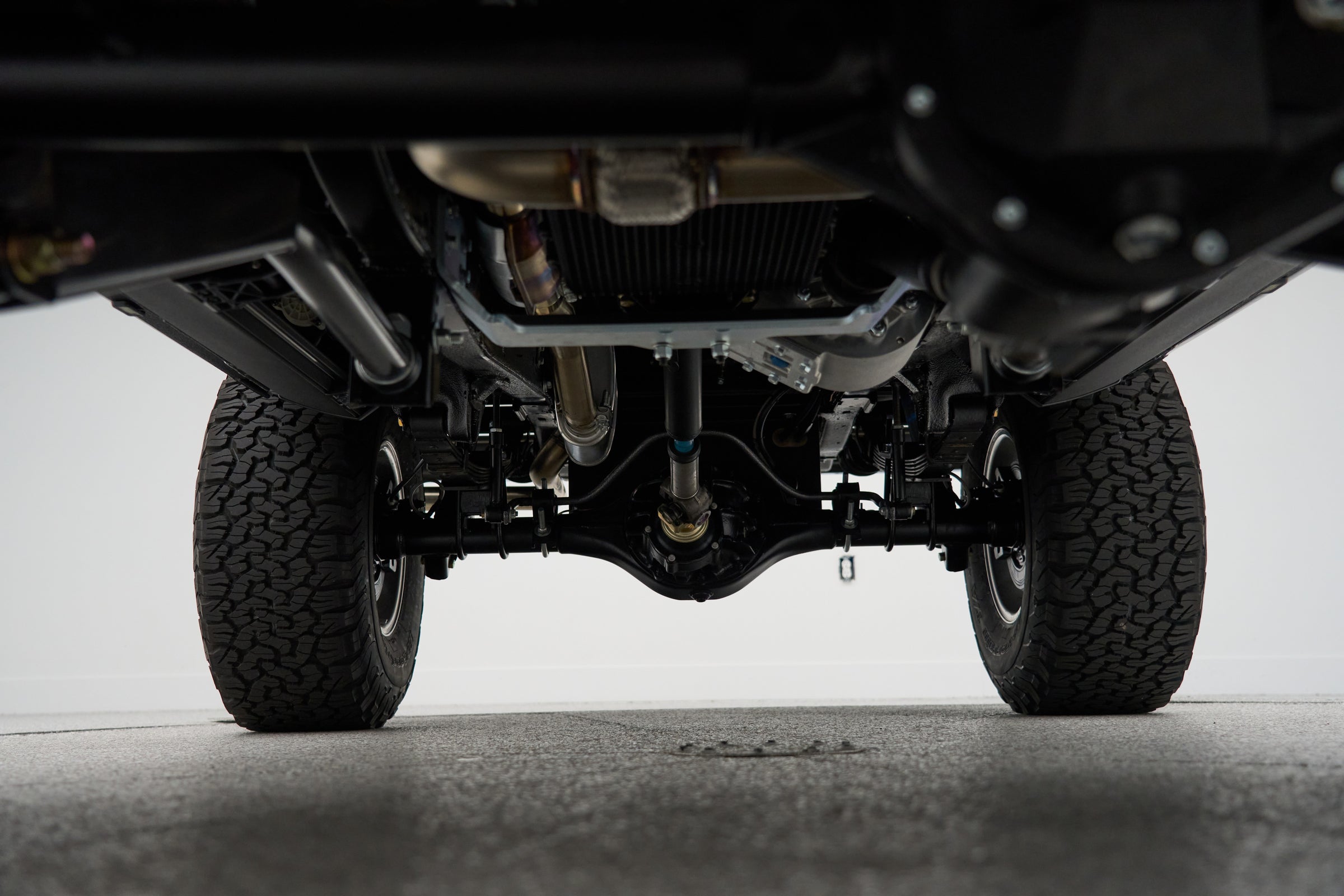 Underside view of front axle and suspension showing solid differential housing and tires