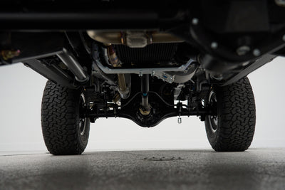 Underside view of front axle and suspension showing solid differential housing and tires