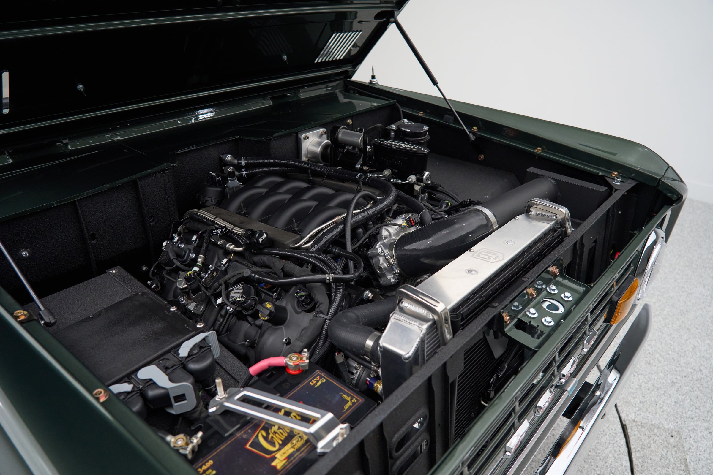 Engine bay of a Classic Ford Bronco showing detailed engine components and battery