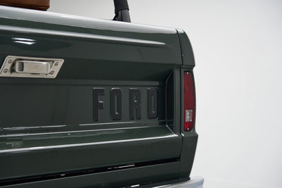 Rear tailgate with raised 'FORD' lettering and taillight on a green Classic Ford Bronco