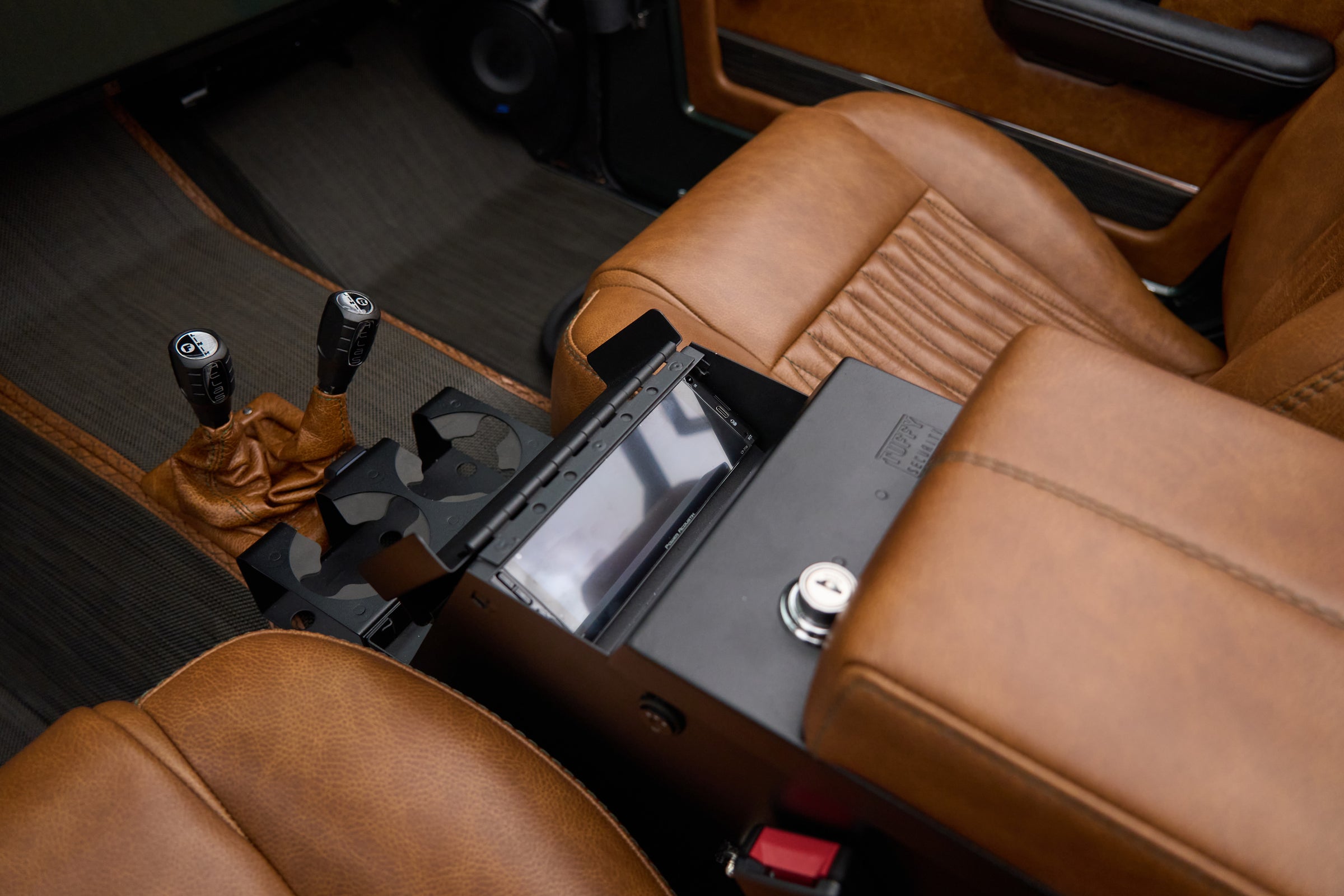 Front seats and console view highlighting brown leather and black control box in Classic Ford Bronco The Drover