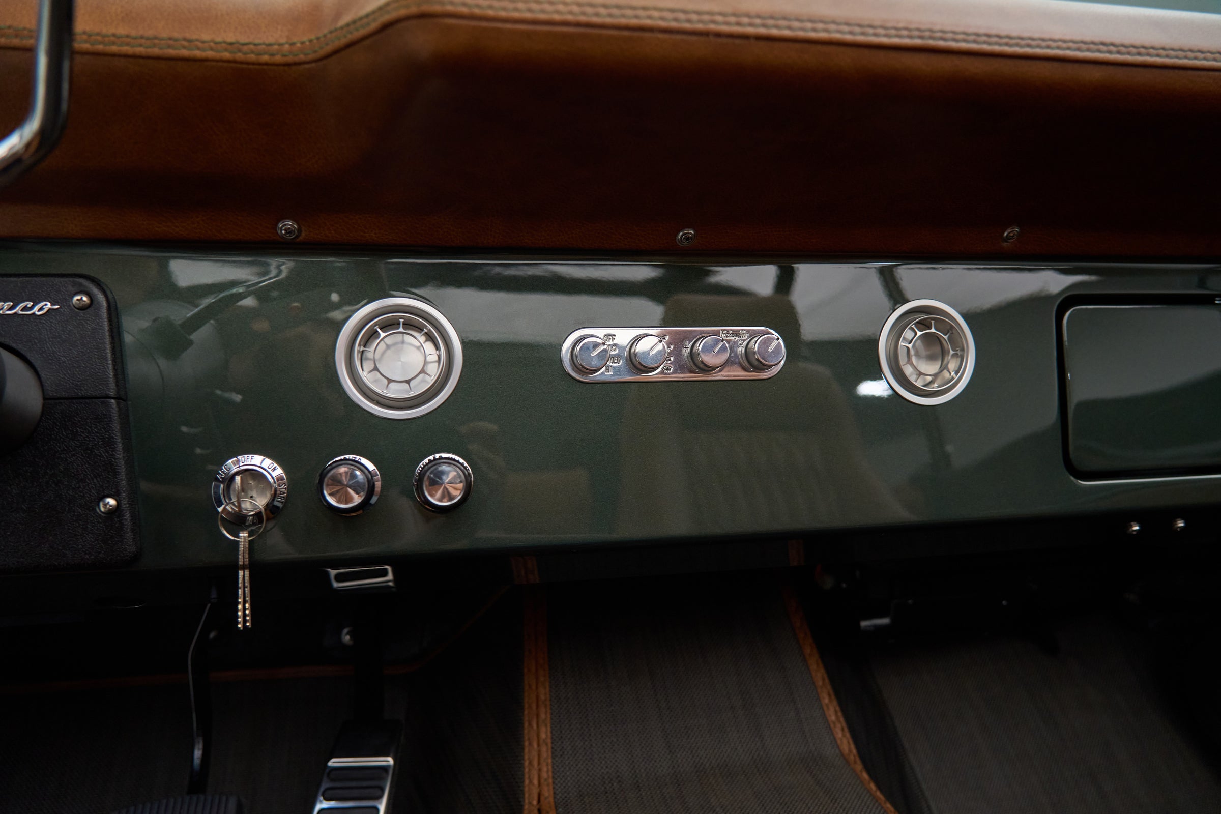 Classic Ford Bronco dashboard with retro-style switches and air vents in green and black.