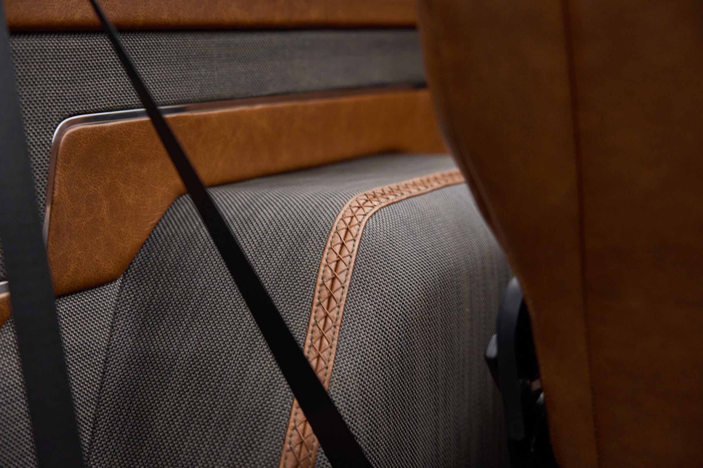 Fabric rear seat with brown leather trim and black seatbelt in Classic Ford Bronco The Drover