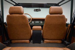 View from rear seats of Classic Ford Bronco The Drover interior showing brown leather front seats and open roof