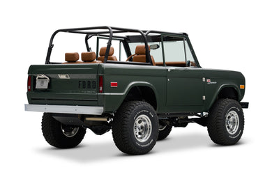 Rear three-quarter view of dark green Classic Ford Bronco with open top and roll cage