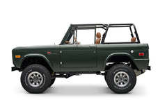 Side view of Classic Ford Bronco in dark green with tan seats, open top and large off-road tires