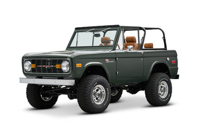 Front three-quarter view of dark green Classic Ford Bronco with round headlights and tan seats