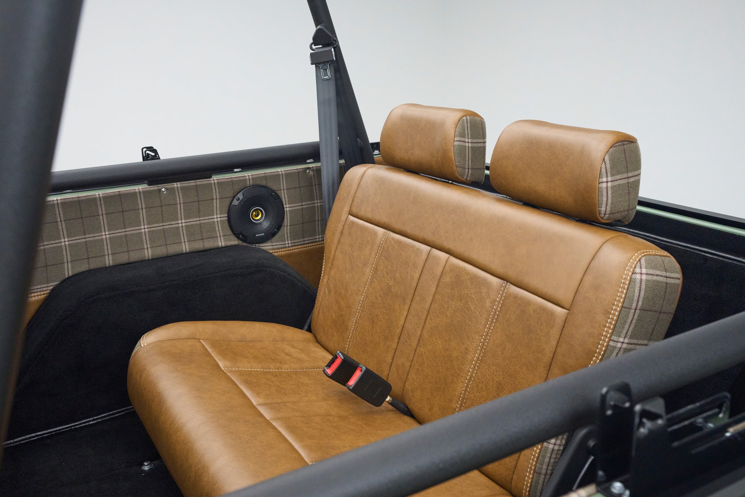 Rear seat inside Classic Ford Bronco with brown leather and plaid accents