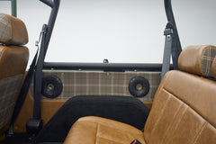 Rear seats of Classic Ford Bronco with tan leather, plaid fabric panels, and black speaker covers