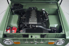 Open hood showing 5.0 engine and clean engine bay of Classic Ford Bronco with green exterior