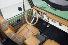 Classic Ford Bronco front interior including wooden steering wheel, dashboard, and plaid seats