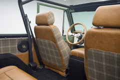 Classic Ford Bronco interior showing driver’s seat with brown leather and plaid upholstery