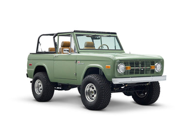 Three quarter front view of green Classic Ford Bronco The Sutton with lifted suspension and open cabin