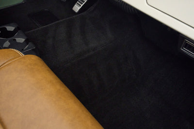 Black carpeted floor area and brown leather seat edge inside Classic Ford Bronco