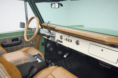 Classic Ford Bronco open door showing dashboard, steering wheel, and plaid leather front seats