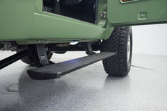Side step and tire of green Classic Ford Bronco with door open