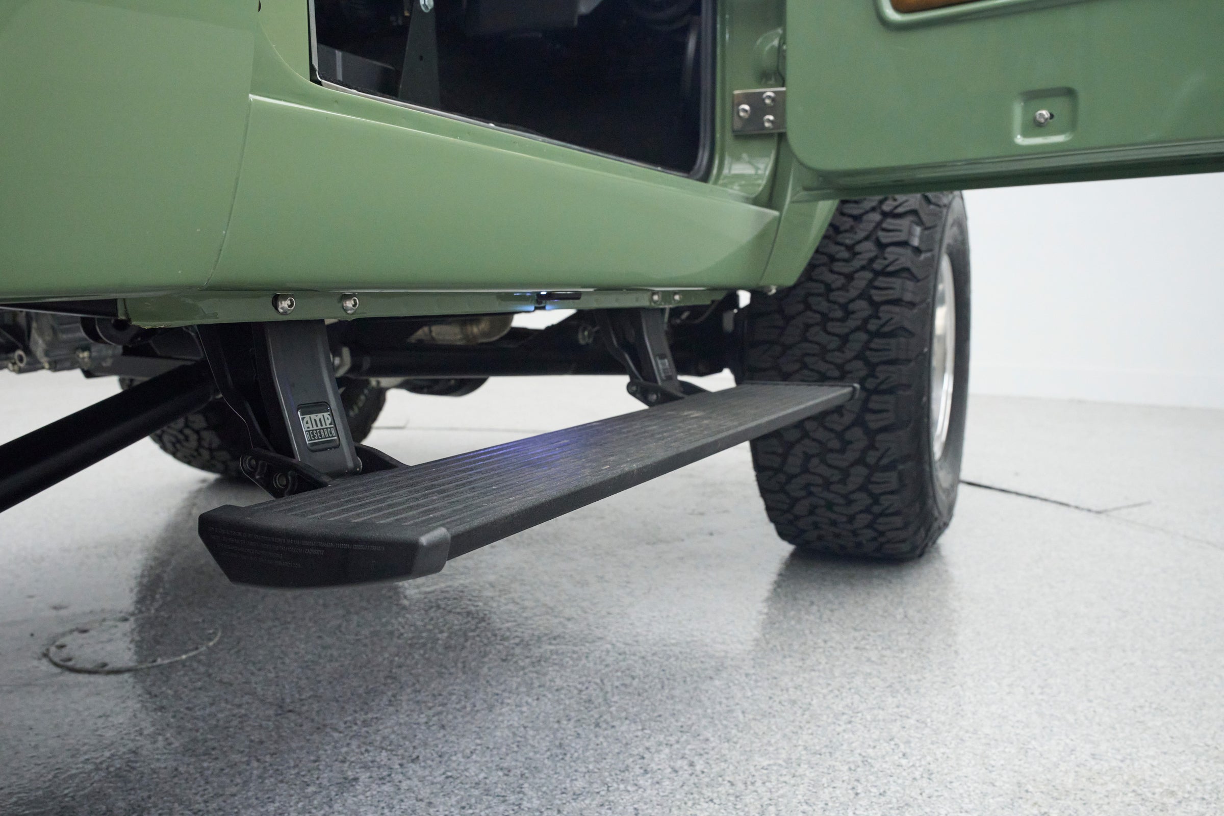 Side step and tire of green Classic Ford Bronco with door open