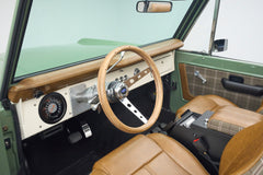 Driver's side interior of Classic Ford Bronco showing steering wheel, instrument cluster, and center console