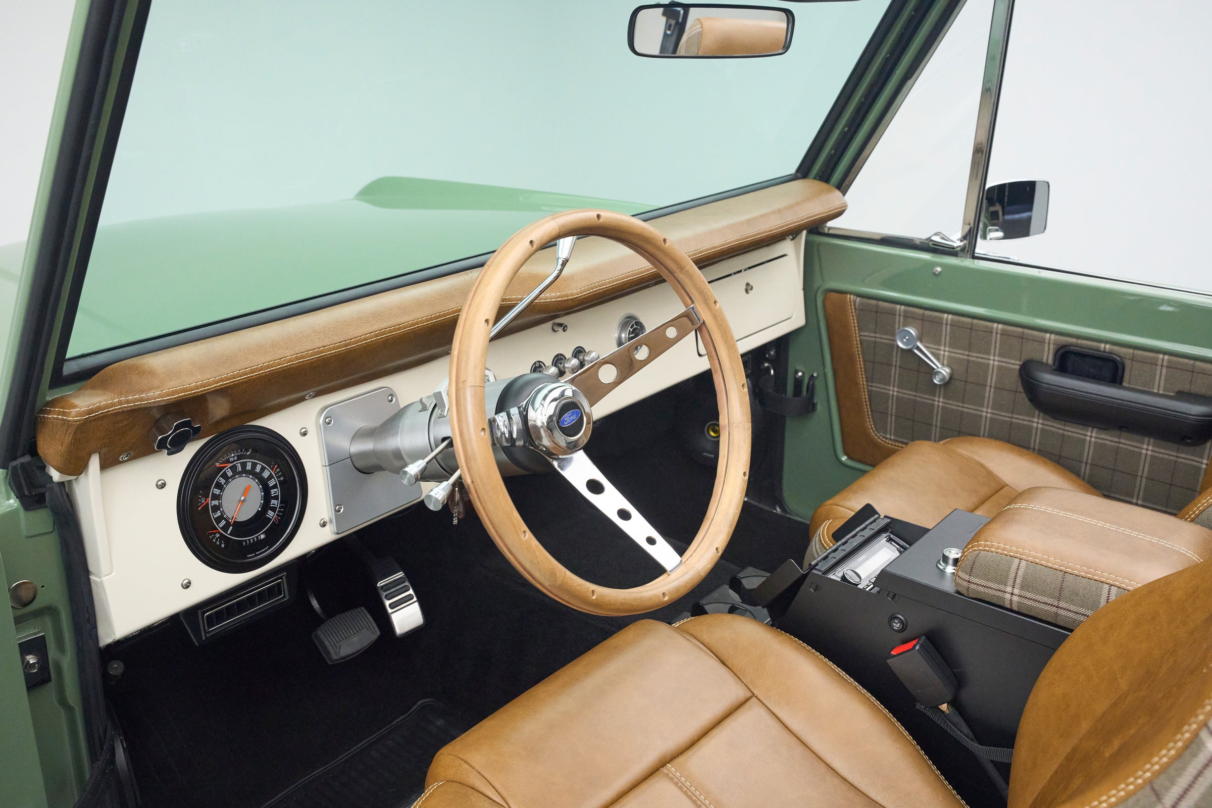 Driver's side interior of Classic Ford Bronco showing steering wheel, instrument cluster, and center console