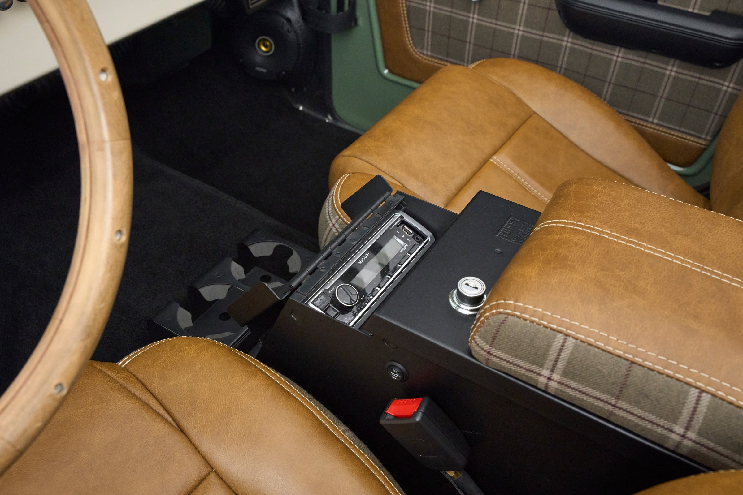 Center console of Classic Ford Bronco showing tan leather seats and radio with opened locking safe