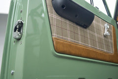 Close-up of green Classic Ford Bronco door interior panel with plaid fabric and brown trim