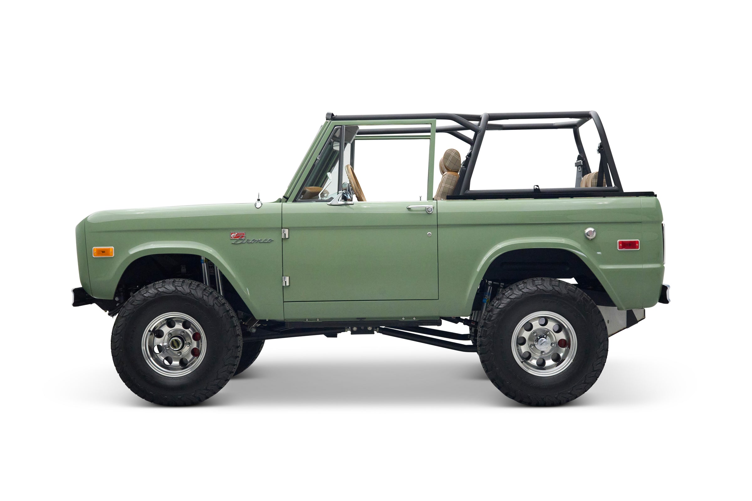 Side view of green Classic Ford Bronco The Sutton showing front door and lifted off-road tires