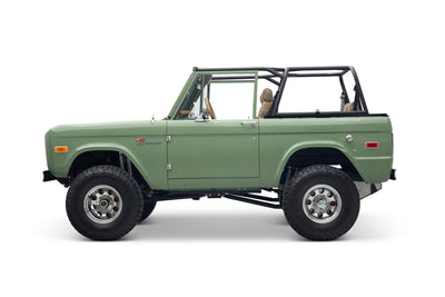 Side view of green Classic Ford Bronco The Sutton showing front door and lifted off-road tires