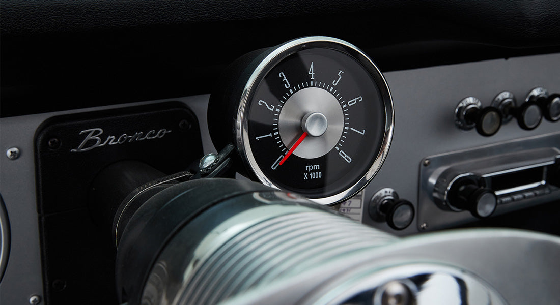 Classic Ford Bronco tachometer mounted on steering column with vintage radio and controls