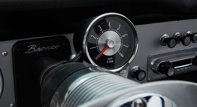 Classic Ford Bronco tachometer mounted on steering column with vintage radio and controls