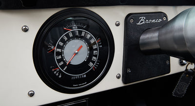 Classic Ford Bronco dashboard with speedometer and tachometer on white background and 'Bronco' label