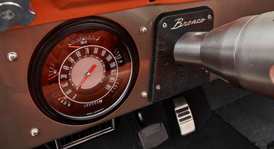 Dashboard cluster with speedometer and Bronco emblem near steering column in Classic Ford Bronco