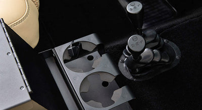 Black cupholder inserts beside two gear shift levers inside a vehicle