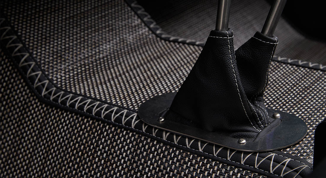 Black leather shifter boots on woven carpet with white stitching in vehicle interior