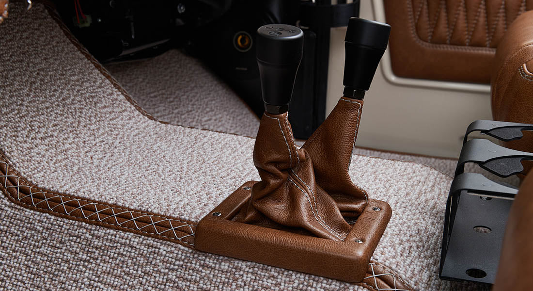 Brown leather shift boot and two gear levers on beige carpet flooring inside Classic Ford Bronco