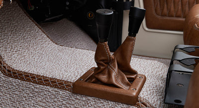 Brown leather shift boot and two gear levers on beige carpet flooring inside Classic Ford Bronco