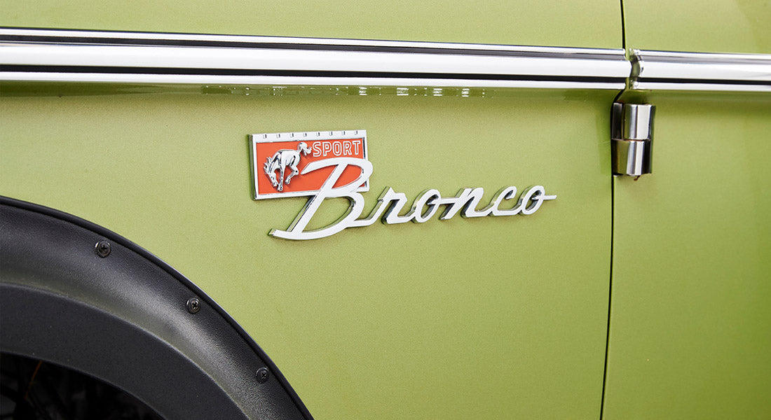 Green door panel of Classic Ford Bronco featuring the Sport Bronco emblem and part of the fender.