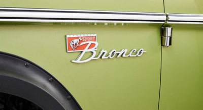 Green door panel of Classic Ford Bronco featuring the Sport Bronco emblem and part of the fender.