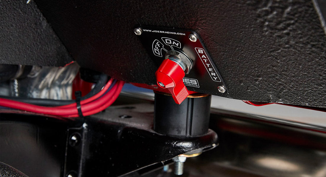 Red battery switch mounted on a black panel with wiring visible