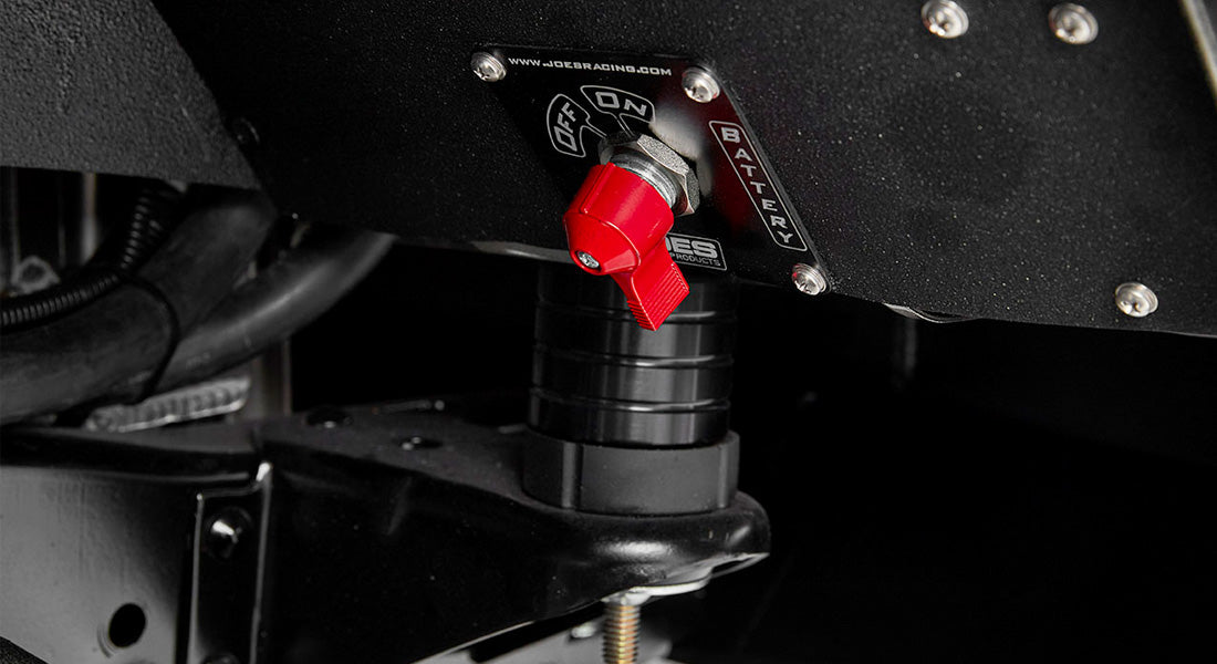 Close-up of red battery disconnect switch mounted on black surface beneath Classic Ford Bronco dashboard